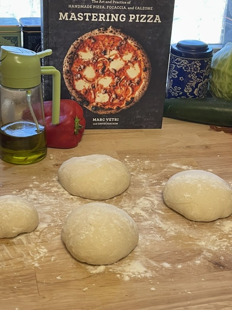 Pizza dough rounds on a floured worktop.