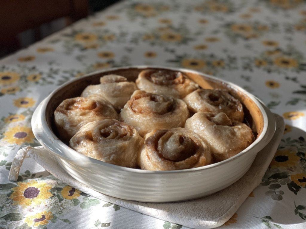 Rolls in a white dish on a sunflower tablecloth.